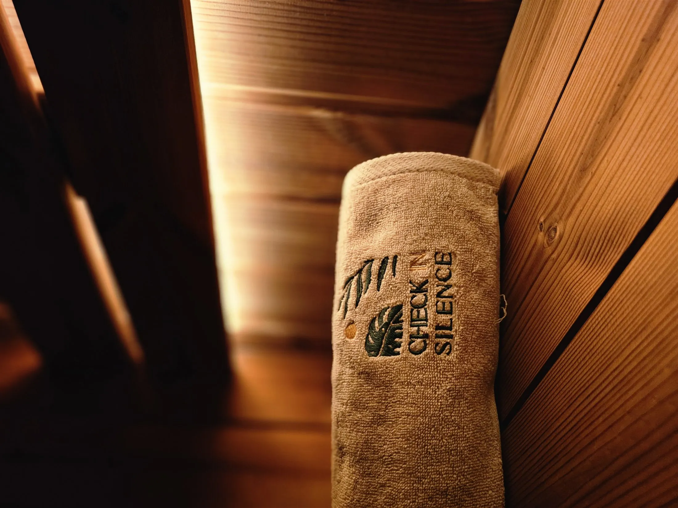 Ręcznik Check in Silence w saunie na tle drewnianych ścian